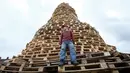 Seorang pria berdiri di tumpukan palet kayu yang akan digunakan membuat api unggun di Ballymacash, Lisburn, Irlandia Utara (10/7). (AFP Photo/Paul Faith)