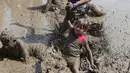 Emily Jamerson jatuh ke dalam kubangan berisi lumpur saat perayaan Mud Day atau Hari Lumpur Tahunan di Westland, Michigan, AS, Selasa (10/7). Dalam Mud Day kali ini para pesertanya yang ikut adalah anak-anak.  (AP/Carlos Osorio)