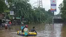 Warga menaiki perahu karet saat melintasi kawasan DI Panjaitan, Jakarta, Selasa (25/2/2020). Hujan yang mengguyur Jakarta sejak dini hari tadi membuat kawasan tersebut terendam banjir sehingga tak bisa dilintasi kendaraan bermotor. (Liputan6.com/Herman Zakharia)
