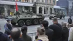 Pejalan kaki menyaksikan kendaraan lapis baja Rusia yang dihiasi bendera merah melaju di sepanjang jalan Tverskaya untuk menghadiri latihan parade militer  Victory Day di Moskow, Jumat (26/4/2024). (AP Photo/Dmitry Serebryakov)