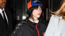 Billie Eilish tampil lebih boyish di after party mengenakan jaket dan baseball cap. Foto: IG/catwalkats].