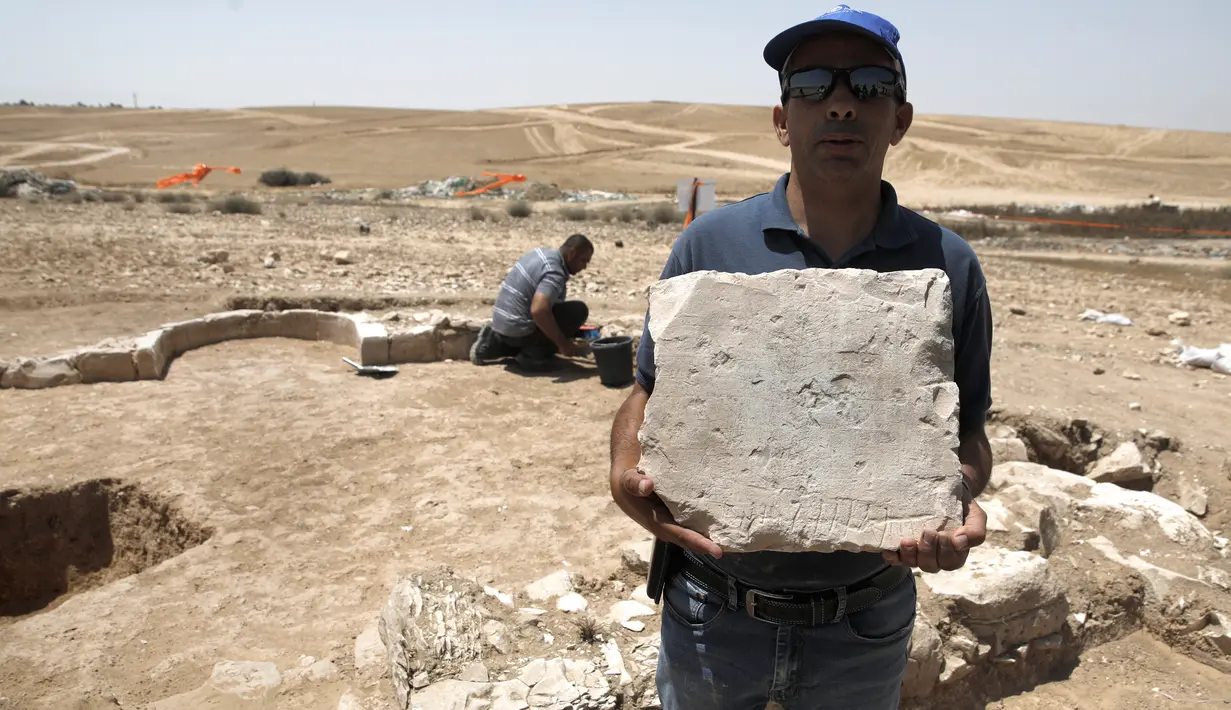 Yaser Alamor dari otoritas barang antik Israel memperlihatkan batu reruntuhan salah satu masjid kuno, di kota Rahat, gurun Negev pada 18 Juli 2019. Peneliti menyebut masjid terkait adalah yang pertama dibangun setelah kedatangan Islam di tempat yang dikenal sebagai Israel. (MENAHEM KAHANA/AFP)