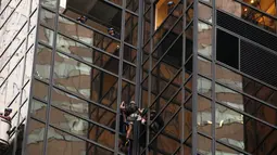 Aksi nekat seorang pria berambut gondrong memanjat gedung Trump Tower di New York, AS, Rabu (10/8). Sejumlah petugas NYPD menunggu pria tersebut sebelum bersiap-siap menahannya ketika mencapai lantai 21. (REUTERS/Lucas Jackson)