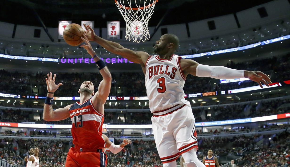 Pemain Chicago Bulls, Dwyane Wade (kanan) menepis bola tembakan pemain Washington Wizards, Marcin Gortat pada laga NBA basketball game di United Center, Chicago, (21/12/2016).  Wizards menang 107-97. (AP/Charles Rex Arbogast)