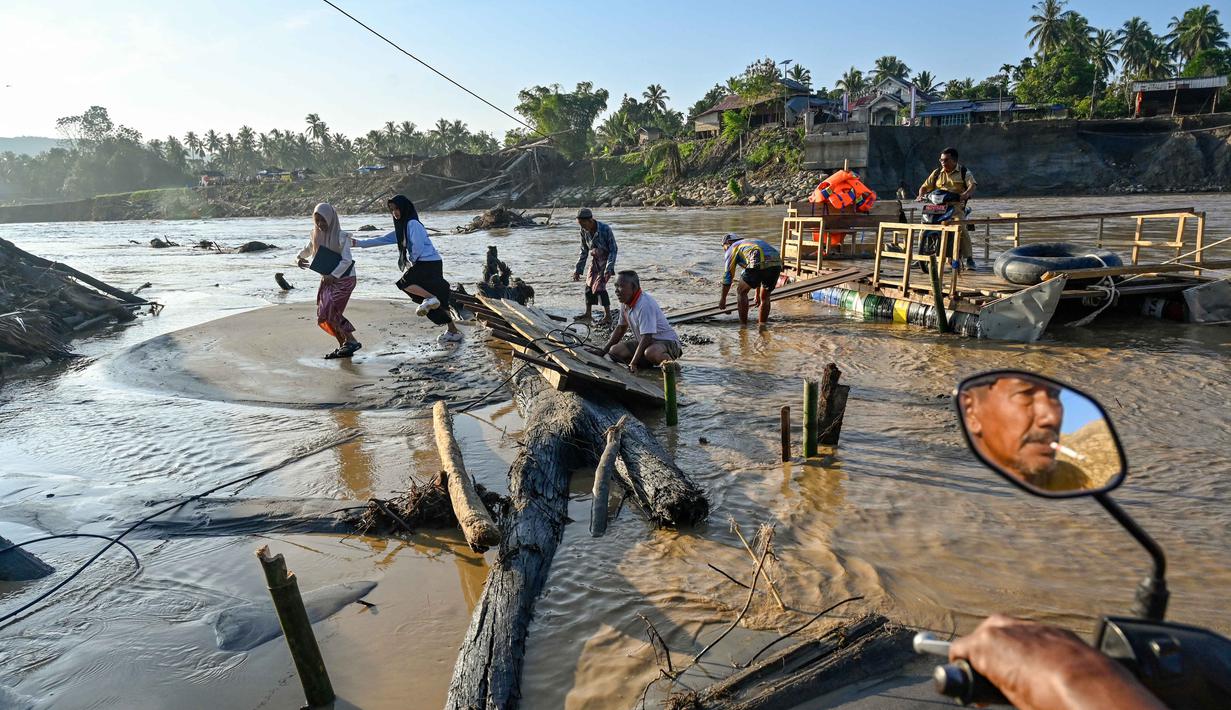 Untuk menyeberangi Sungai Peusangan Bireuen Aceh, warga terpaksa menggunakan rakit kayu sederhana yang ditarik dengan tali atau kabel baja (seling). Tampak dalam foto, masyarakat menggunakan rakit tali untuk menyeberangi Sungai Peusangan menyusul banjir bandang yang menghancurkan desa-desa di sekitarnya di Kabupaten Bireuen, provinsi Aceh, pada Senin 5 Januari 2026. (CHAIDEER MAHYUDDIN/AFP)