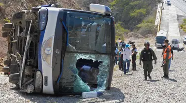 Petugas berdiri di dekat bus yang terbalik di jalan raya Caracas-La Guaira di Caracas, Venezuela, Rabu (10/2). Bus yang mengangkut pemain tim sepak bola Argentina Huracan itu kecelakaan saat menuju Bandara Internasional Simon Bolivar. (AFP/FEDERICO PARRA)