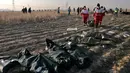 Tim penyelamat mengumpulkan jasad korban jatuhnya pesawat Boeing 737-800 di Shahedshahr, Iran, Rabu (8/1/2020). Pesawat sempat terbakar di udara sebelum akhirnya jatuh di lahan pertanian. (AP Photo/Ebrahim Noroozi)