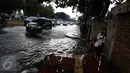 Pejalan kaki melintasi genangan air di kawasan Jalan Merdeka Timur, Jakarta, Selasa (1/11). Hujan deras disertai angin yang mengguyur wilayah Jakarta, mengakibatkan genangan di sejumlah ruas jalan. (Liputan6.com/Faizal Fanani)