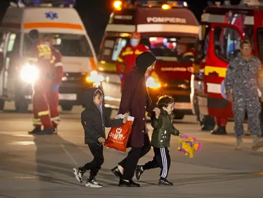 Seorang perempuan dan dua anak, dievakuasi dari Gaza, tersenyum saat berjalan di landasan setelah tiba dari Mesir di pangkalan angkatan udara Baza 90 di Otopeni, Rumania, Rabu, 8 November 2023. (AP Photo/Andreea Alexandru)