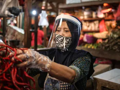 Salah satu pedagang menggunakan face shield dan sarung tangan saat melayani pembeli di Pasar Senen, Jakarta, Senin (1/6/2020). Kementerian Perdagangan menyiapkan pedoman bagi penyelenggara kegiatan perdagangan untuk diterapkan pada saat kenormalan baru (new normal). (Liputan6.com/Faizal Fanani)