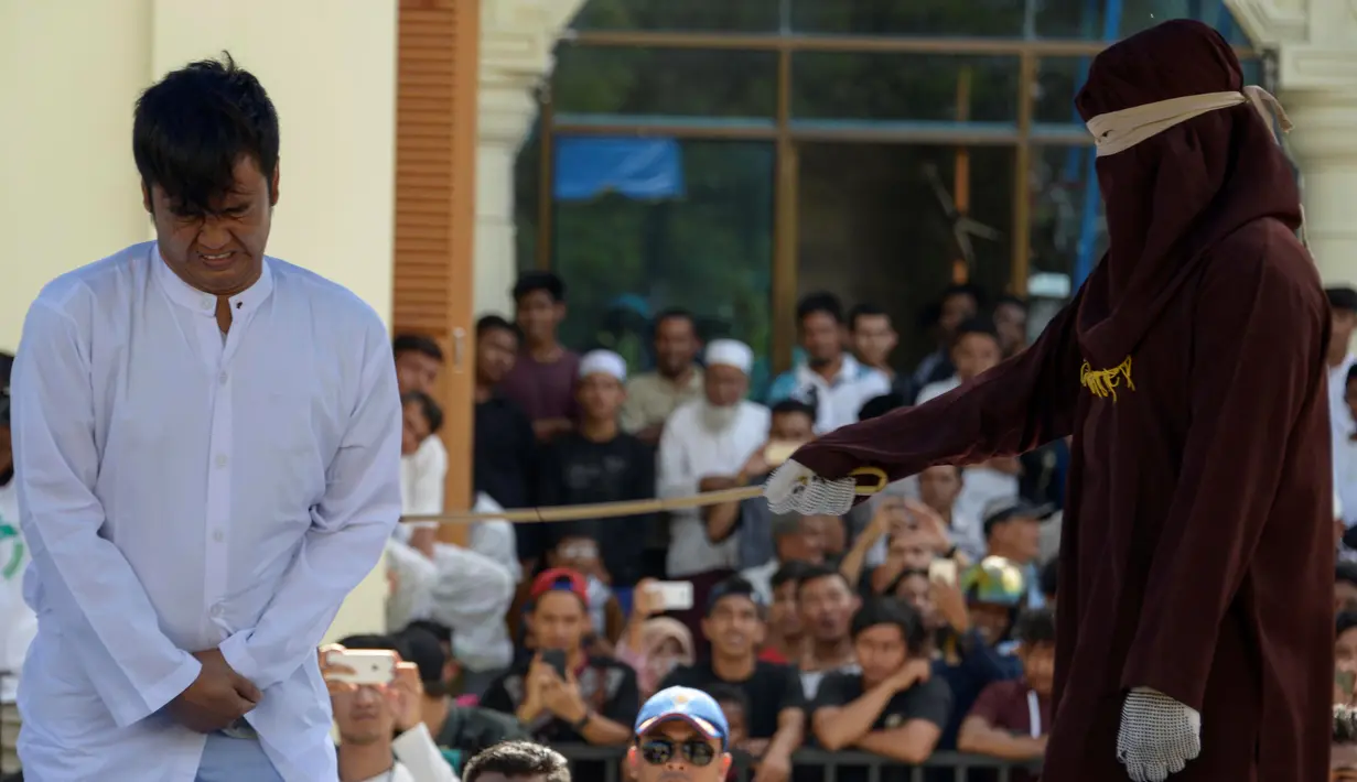 Petugas syariah mencambuk salah satu pasangan gay di depan Masjid Baiturrahim, Aceh (13/7). Nyakrab dan Rustam divonis hukuman cambuk sebanyak 90 kali, saat eksekusi cambukan dipotong menjadi 87 kali karena pengurangan masa tahanan. (AP Photo/Heri Juanda)