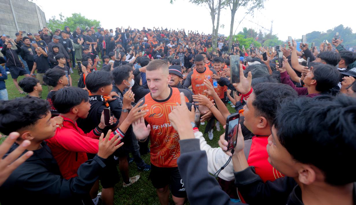 Selain adu gengsi, laga antara Persija Jakarta dan Persib Bandung kali ini akan menentukan tim mana yang akan duduk di puncak klasemen tengah musim BRI Super League musim 2025/2026. Tampak dalam foto, pendukung Persija Jakarta atau The Jakmania menyambut pemain yang akan berlatih di Persija Training Ground, Bojong Sari, Depok, Jawa Barat, Jumat (9/1/2026). (Bola.com/M Iqbal Ichsan)