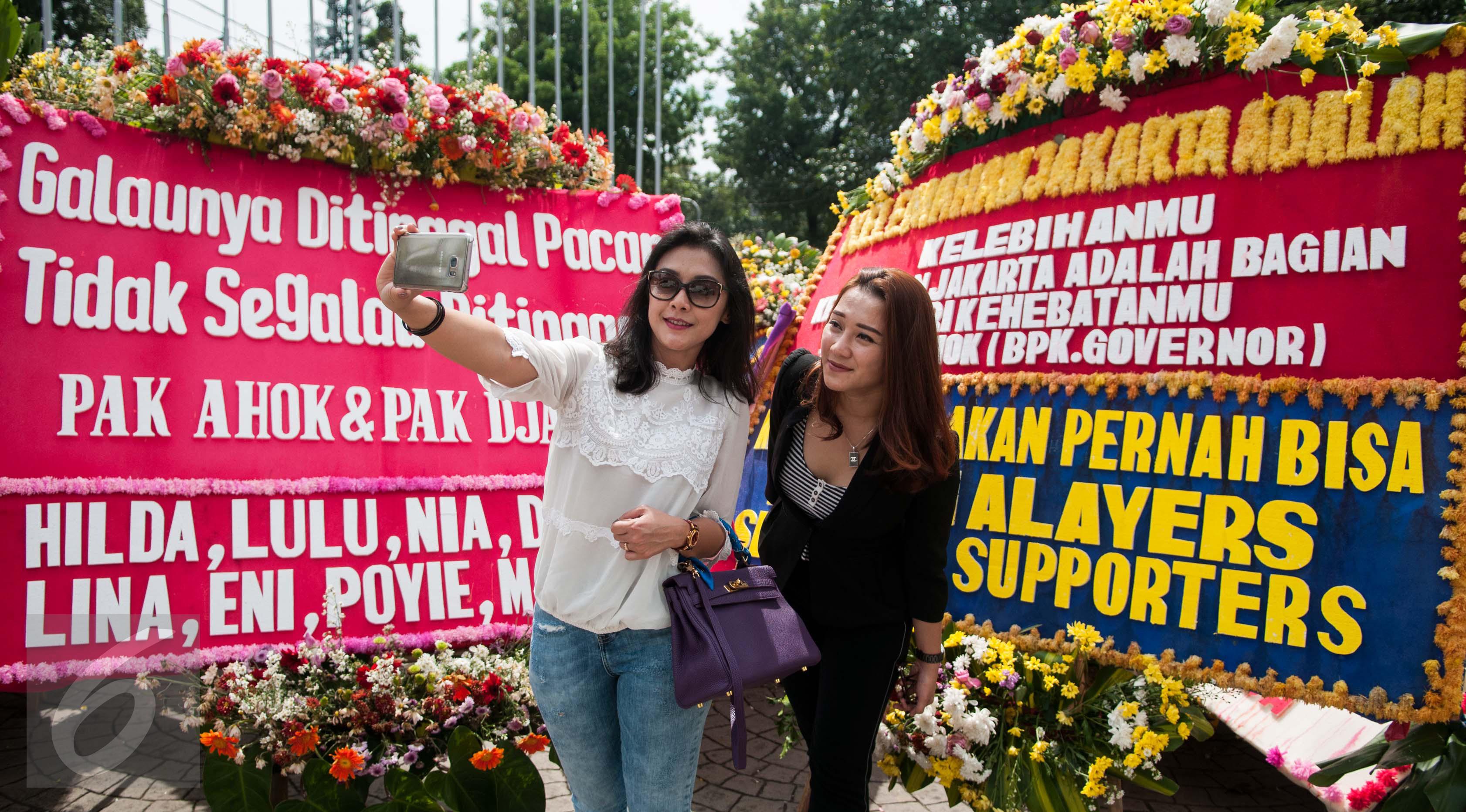 Warga berswafoto di depan karangan bunga untuk Gubernur dan Wakil Gubernur DKI Jakarta Basuki T Purnama (Ahok) dan Djarot Syaiful Hidayat di Balai Kota Jakarta, Rabu (28/4). (Liputan6.com/Gempur M Surya)