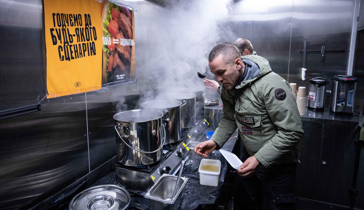 Hingga Minggu (25/1/2026), sekitar 1.700 gedung apartemen di Kyiv masih belum mendapatkan pasokan pemanas. Tampak dalam foto, para veteran the 3rd Separate Assault Brigade Angkatan Bersenjata Ukraina menyajikan makanan panas gratis bagi orang-orang di lingkungan perumahan yang rumahnya tanpa listrik setelah serangan udara Rusia berulang kali terhadap sektor energi negara itu di Kyiv, Selasa 27 Januari 2026. (AP Photo/Danylo Antoniuk)
