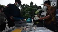 Petugas menata barang bukti dalam rilis tindak pidana pemalsuan surat hasil tes PCR dan swab antigen di Polda Metro Jaya, Selasa (13/7/2021). Petugas mengamankan barang bukti dokumen pembuatan surat swab antigen dan PCR palsu dengan tarif Rp170 - Rp 300 ribu. (merdeka.com/Imam Buhori)