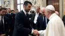 Paus Fransiskus (kanan) bersalaman dengan Kiper Juventus, Gianluigi Buffon di akhir audiensi dengan pemain Juventus dan Lazio pada malam menjelang final Piala Tim pada 16 Mei 2017. (AFP/Osservatore Romano)
