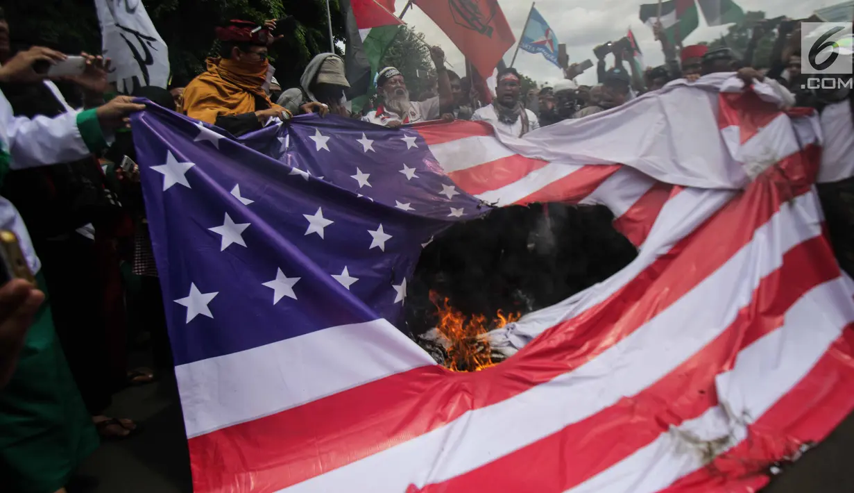 Pengunjuk rasa membakar bendera Amerika Serikat dan foto Donald Trump saat berunjuk rasa di depan Kedubes AS, Jakarta, Senin (11/12). Mereka menolak klaim sepihak Presiden Donald Trump soal Yerusalem sebagai Ibu Kota Israel. (Liputan6.com/Faizal Fanani)