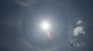 Pesawat komersil melintas dilatari fenomena halo matahari di Meksiko, Sabtu (7/7). Fenomena halo matahari terjadi karena pembiasan kristal es yang berada di sekitar matahari sehingga membentuk cincin pelangi yang mengelilingi matahari (AP/Moises Castillo)