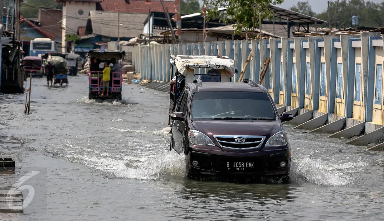 Sebuah mobil melintas di jalan yang tergenang air di Muara Angke, Jakarta, Senin (2/1). Rencananya Pemprov DKI akan membuat tanggul penahan air rob di kawasan tersebut. (Liputan6.com/Faizal Fanani)