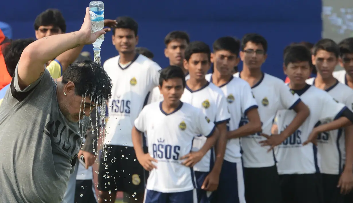 Legenda sepak bola, Diego Maradona, melepas dehidrasi usai memberikan pelatihan kepada anak-anak di Barasat, Selasa (12/12/2017). Kunjungan ini dilakukan pria asal Argentina itu dalam rangkaian liburan. (AFP/Dibyangshu Sarkar)