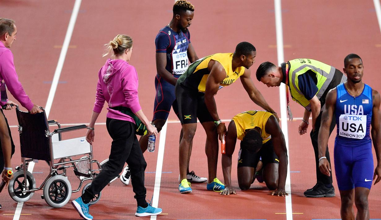 Pelari Jamaika, Usain Bolt mendapat perawatan usai terjatuh karena cedera di final 4x100 meter pada Kejuaraan Dunia Atletik, Sabtu (12/8). Pemegang rekor pelari tercepat di dunia itu terkapar di lintasan dan gagal melanjutkan lomba. (AP/Martin Meissner)