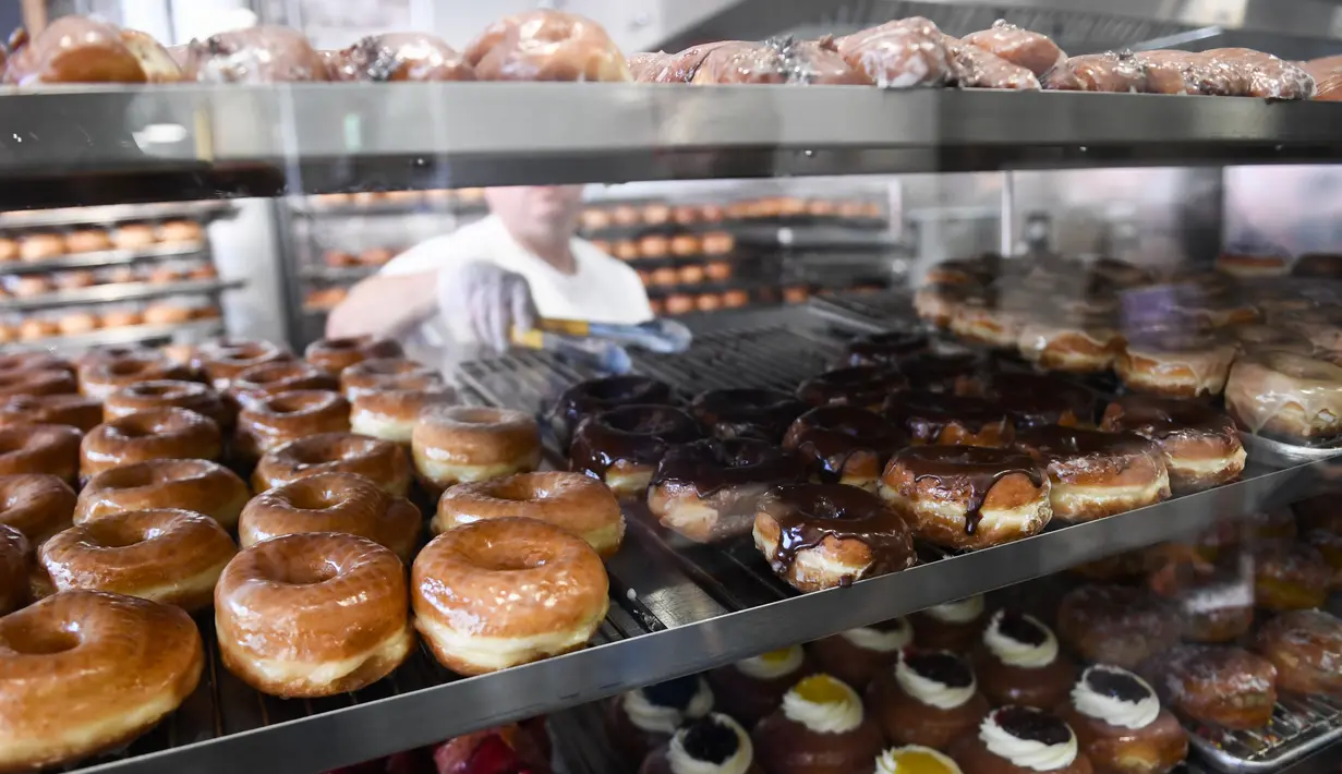 Pekerja mengemas donat dan kue kering untuk pelanggan di The Donut Man, Grand Central Market di pusat kota Los Angeles, AS, Jumat (11/3/2022). Ekonomi terbesar dunia itu terus dihantam oleh gelombang inflasi, yang diperkirakan akan memburuk akibat serangan Rusia ke Ukraina. (Patrick T. FALLON/AFP)