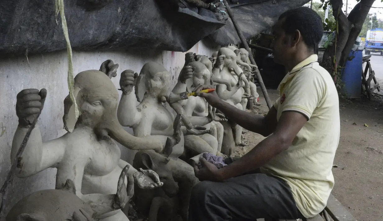 Perajin membuat patung Dewa Ganesha di sebuah bengkel di pinggiran Hyderabad, India, Rabu (18/8/2021). ​Patung ramah lingkungan yang dibuat jelang perayaan Ganesh Chaturthi tersebut dibuat dari lumpur, serat rami, dan bambu untuk mengurangi polusi air. (NOAH SEELAM/AFP)