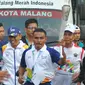 Petinju legendaris Indonesia, Nico Thomas, membawa obor Asian Games XVIII saat melintasi di Kota Malang, Jawa Timur, Jumat (20/7/2018). Sebanyak 10 kota di Indonesia akan dilalui oleh obor Asian Games. (Bola.com/Iwan Setiawan)