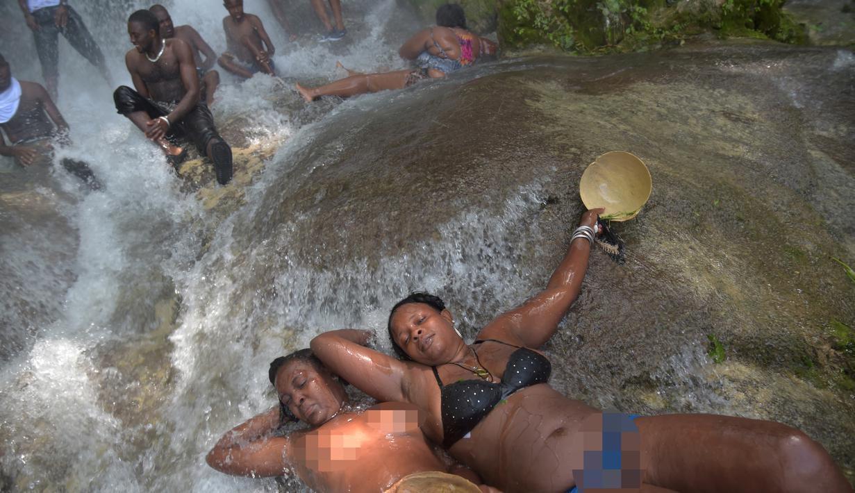 Seorang wanita bertelanjang dada mandi di bawah air terjun di Saut d' Eau, Haiti (15/7). Menurut kepercayaan setempat, Perawan del Carmen muncul di tempat ini di atas pohon palem pada tanggal 16 Juli 1847. (AFP Photo/Hektor Retamal)
