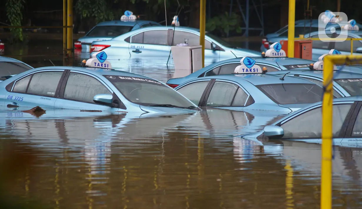 Sejumlah taksi terendam banjir di Pool Taksi Bluebird kawasan Kramat Jati, Jakarta, Selasa (25/2/2020). Meluapnya Kali Cipinang membuat Pool Taksi Blue Bird yang berada tepat di samping kali ikut terdampak banjir. (Liputan6.com/Herman Zakharia)