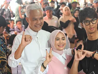 Calon Presiden nomor urut 3, Ganjar Pranowo bersama istrinya Siti Atiqoh Supriyanti dan putranya Muhammad Zinedine Alam Ganjar (kiri ke kanan) menunjukkan jari-jari mereka usai memberikan suara dalam pemilihan umum (Pemilu) serentak 2024 di Semarang, Jawa Tengah pada 14 Februari 2024. (JUNI KRISWANTO/AFP)