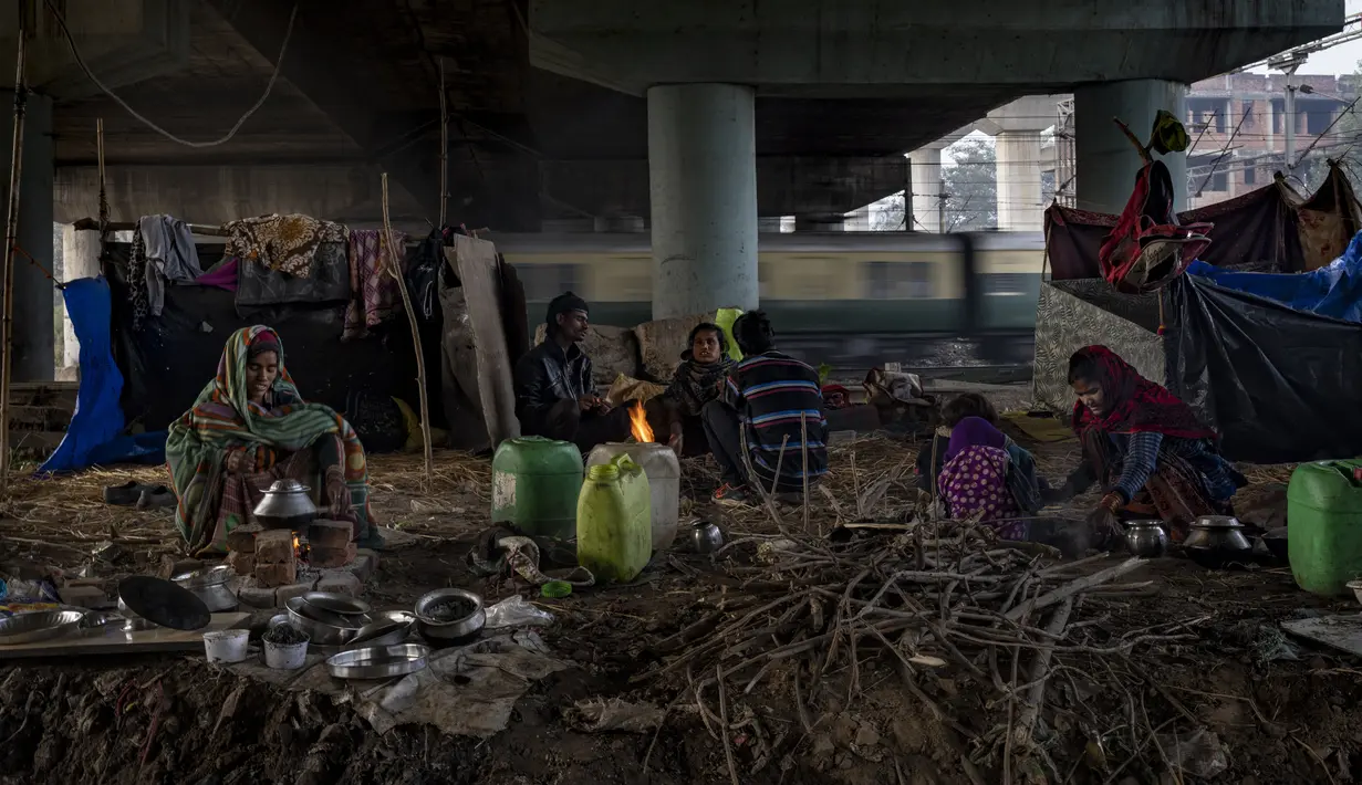Para tunawisma beristirahat di sepetak tanah di bawah jembatan penyeberangan di sebelah rel kereta api pada pagi yang dingin di New Delhi, 30 Desember 2022. Musim dingin yang keras disalahkan karena membunuh puluhan tunawisma dan membuat puluhan ribu lainnya menggigil di jalanan. (AP Photo/Altaf Qadri)