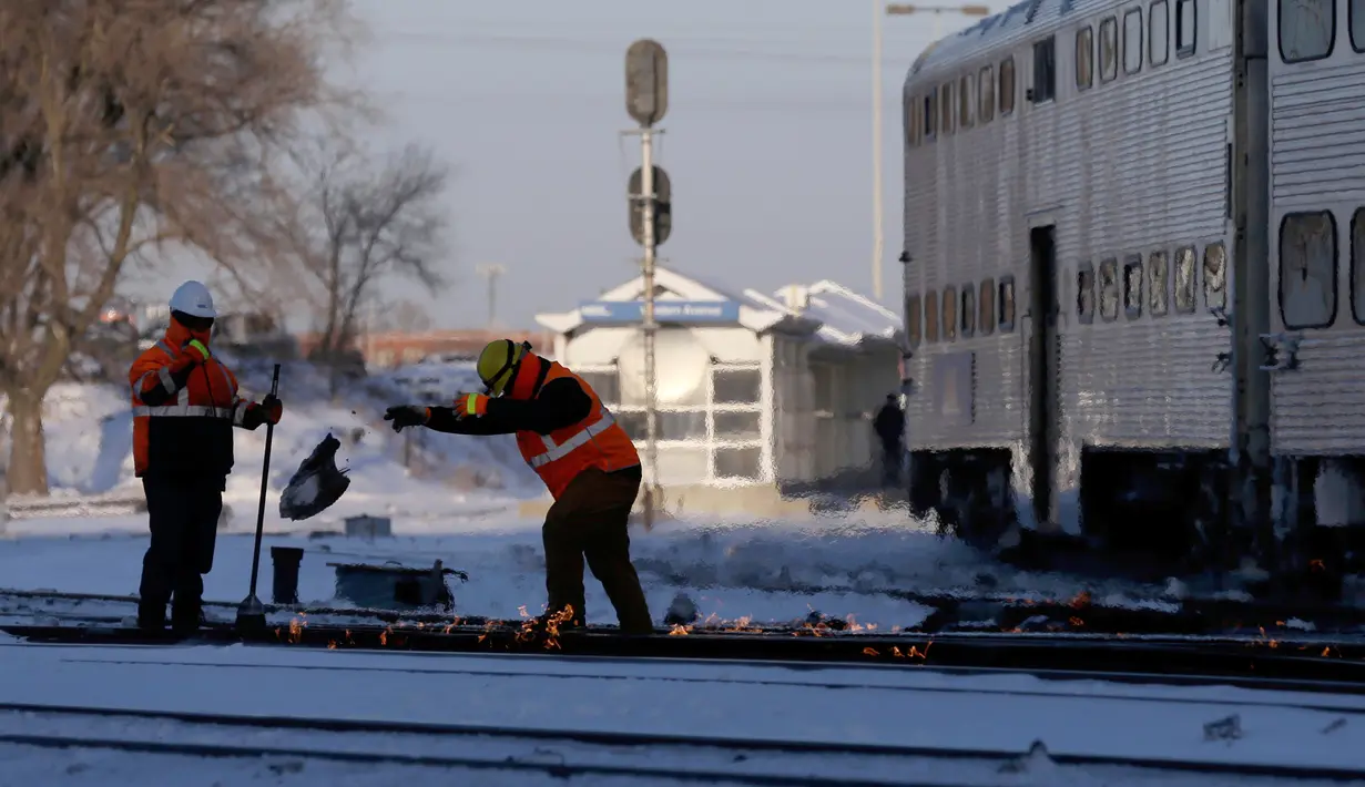 Petugas berupaya menghangatkan lintasan rel kereta di dekat stasiun Metra Western Avenue, Chicago, 29 Januari 2019. Metra memakai sistem pemanas berbahan bakar gas untuk menghangatkan lintasan di tengah suhu udara yang sangat dingin. (AP/Kiichiro Sato)