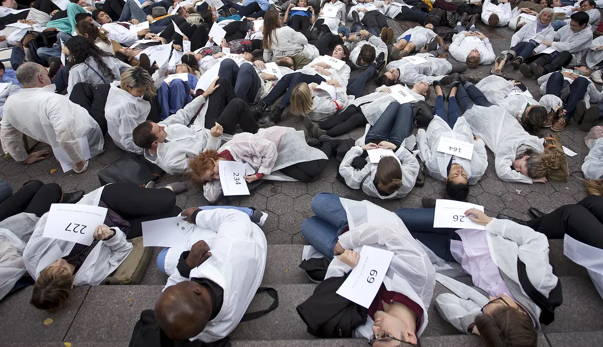 Petugas medis dari segala bidang menggelar aksi protes dengan merebahkan badan mereka dijalanan atau disebut gerakan "die-in" di New York, (29/10/2015). Hal ini menyinggung perihal perang di Suriah yang menewakan 700 petugas medis. (REUTERS/Carlo Allegri)