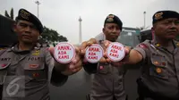 Petugas kepolisian menunjukan pin saat melakukan pengamanan di kawasan Monas, Jakarta, Selasa (18/4). Polda Metro Jaya dan Kodam Jaya mengerahkan 64.523 personel gabungan untuk mengawal Pilkada DKI 2017 putaran kedua. (Liputan6.com/Faizal Fanani)