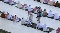 Petugas membagikan air zam-zam kepada para jemaah yang melaksanakan salat Idul Fitri di Masjidil Haram, Mekah, Arab Saudi, Minggu (24/5/2020). Salat Idul Fitri tetap digelar di Masjidil Haram dan Masjid Nabawi namun dengan jemaah terbatas. (AFP)