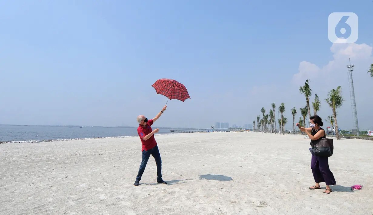 Warga berfoto di hamparan pasir putih White Sand Beach, Pantai Indah Kapuk (PIK) 2, Jakarta Utara, Sabtu (5/6/2021). Hamparan pasir putih buatan sepanjang sekitar 4 Km menjadi salah satu destinasi warga Jabotabek untuk berlibur. (merdeka.com/Arie Basuki)