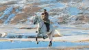 Pemimpin Korea Utara Kim Jong-un menunggangi kuda putih  saat salju yang turun di gunung Paektu (16/10/2019). Kim Jong-un tampil mengenakan kaca mata dengan mantel tebal berwarna coklat.  (Photo by STR/KCNA VIA KNS/AFP)