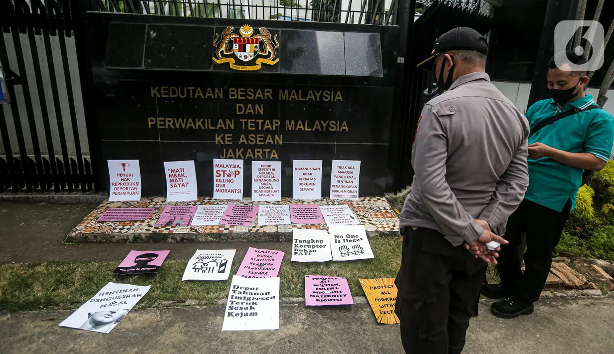 Seorang polisi melihat sejumlah poster yang ditaruh buruh migran saat menggelar aksi di depan Kedutaan Besar Malaysia, Jakarta, Selasa (9/8/2022). Mereka menuntut pemerintah Malaysia melakukan perbaikan dan menghentikan berbagai praktik kejam di dalam pusat tahanan imigrasi. (Liputan6.com/Faizal Fanani)