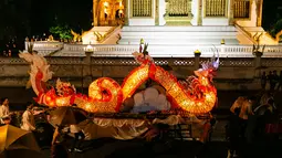 Warga mengikuti parade bersama perahu naga di Luang Prabang, Laos, 3 Oktober 2020. Dalam Festival Boun Lai Heua Fai, warga mendandani kota dengan berbagai lentera, berparade bersama, kemudian melarungkan perahu naga besar dan kecil dari batang pohon pisang ke Sungai Mekong. (Xinhua/Kaikeo Saiyasane)