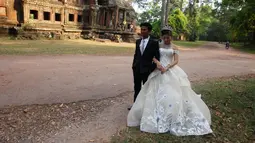 Sepasang pengantin baru melakukan foto pernikahan mereka di kompleks kuil Angkor Wat, sebuah candi ikonik dan bersejarah di Kamboja, 14 Maret 2018. Candi ini dibangun pada pertengahan abad ke-12 dan memakan waktu selama 30 tahun. (AP Photo/Heng Sinith)
