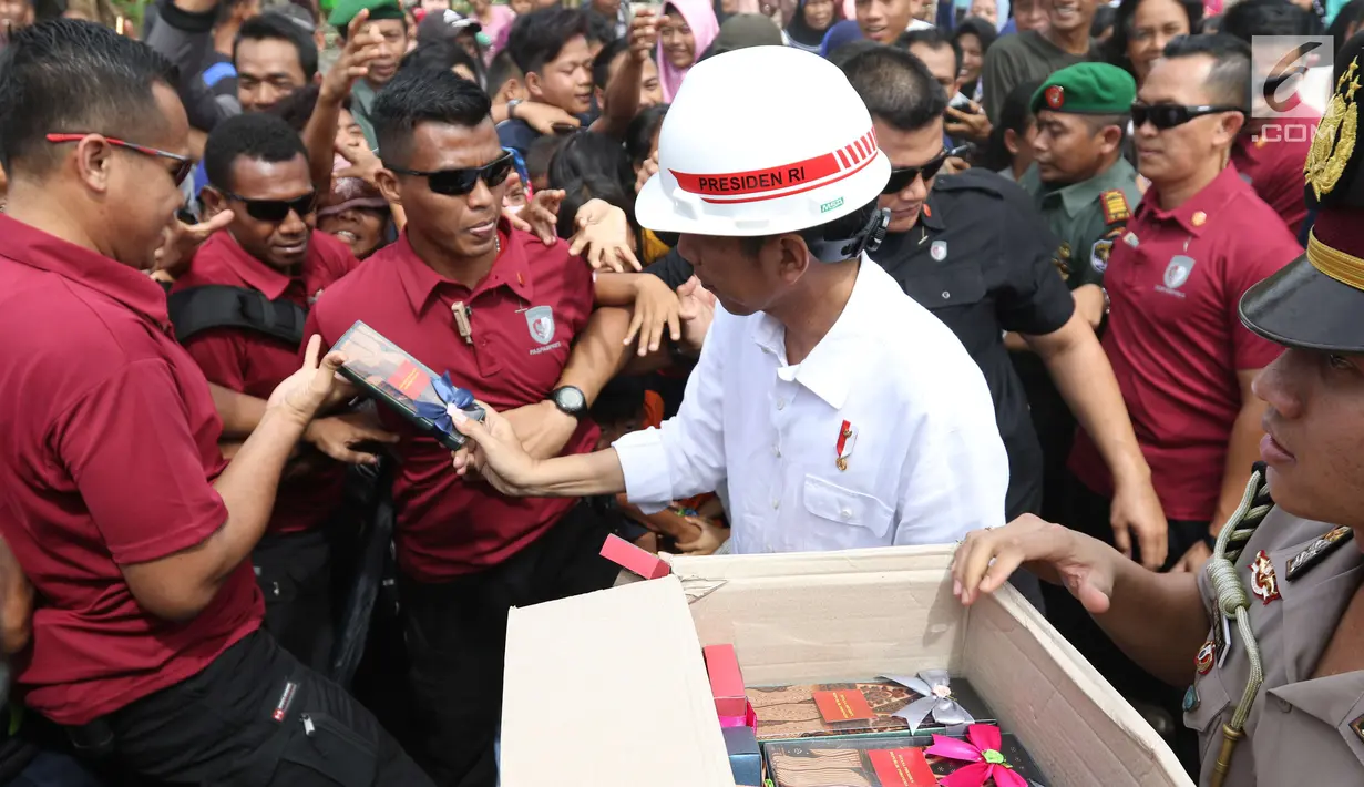 Presiden Joko Widodo atau Jokowi saat membagikan buku dan kain batik kepada warga sekitar Bandara Soetta, Tangerang, Banten, Kamis (21/6). Bagi-bagi buku tersebut merupakan rutinitas Jokowi usai blusukan. (Liputan6.com/Angga Yuniar)