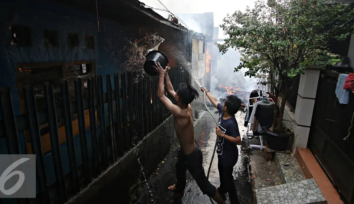 Warga menyiram rumah yang terbakar di Jalan Gelora IX A, Palmerah, Jakarta, Kamis (4/8). Api yang diduga berasal dari arus pendek itu membakar 8 rumah. (Liputan6.com/Immanuel Antonius)