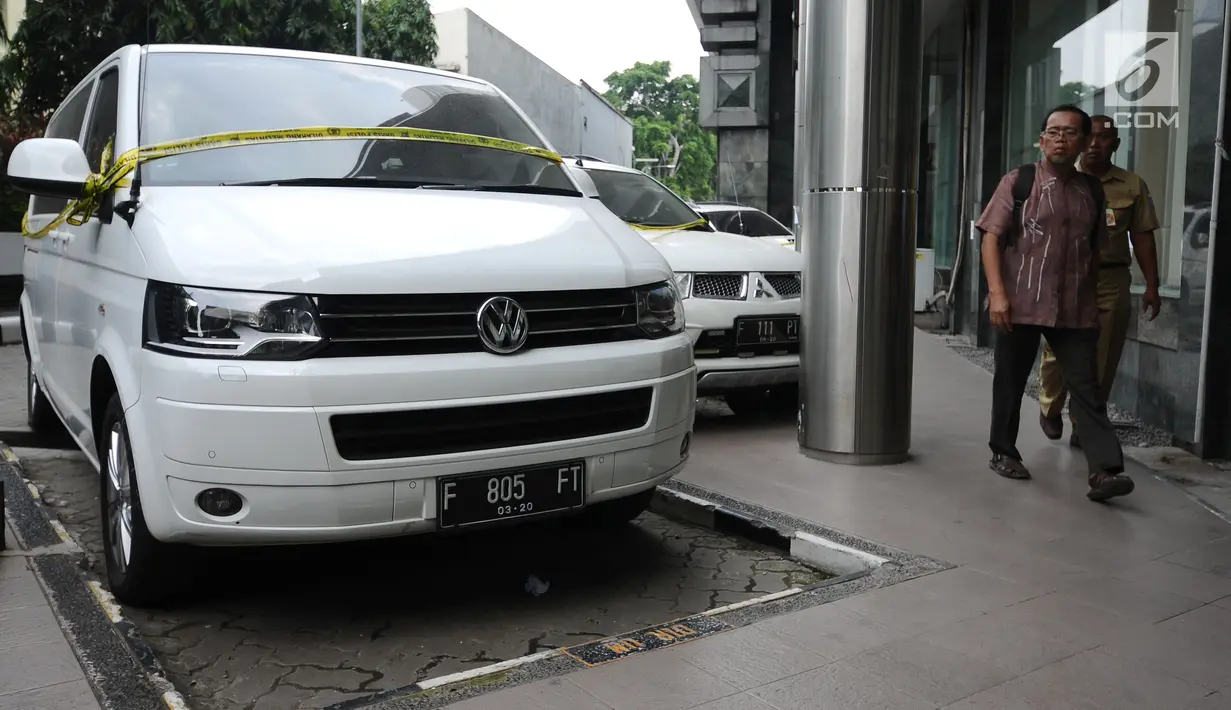  Warga melintasi mobil milik tersangka kasus penipuan calon jamaah umroh yang disita Bareskrim Mabes Polri, Jakarta, Selasa (22/8). Hingga kini, polisi telah menetapkan tiga tersangka kasus tersebut. (Liputan6.com/Helmi Fithriansyah)