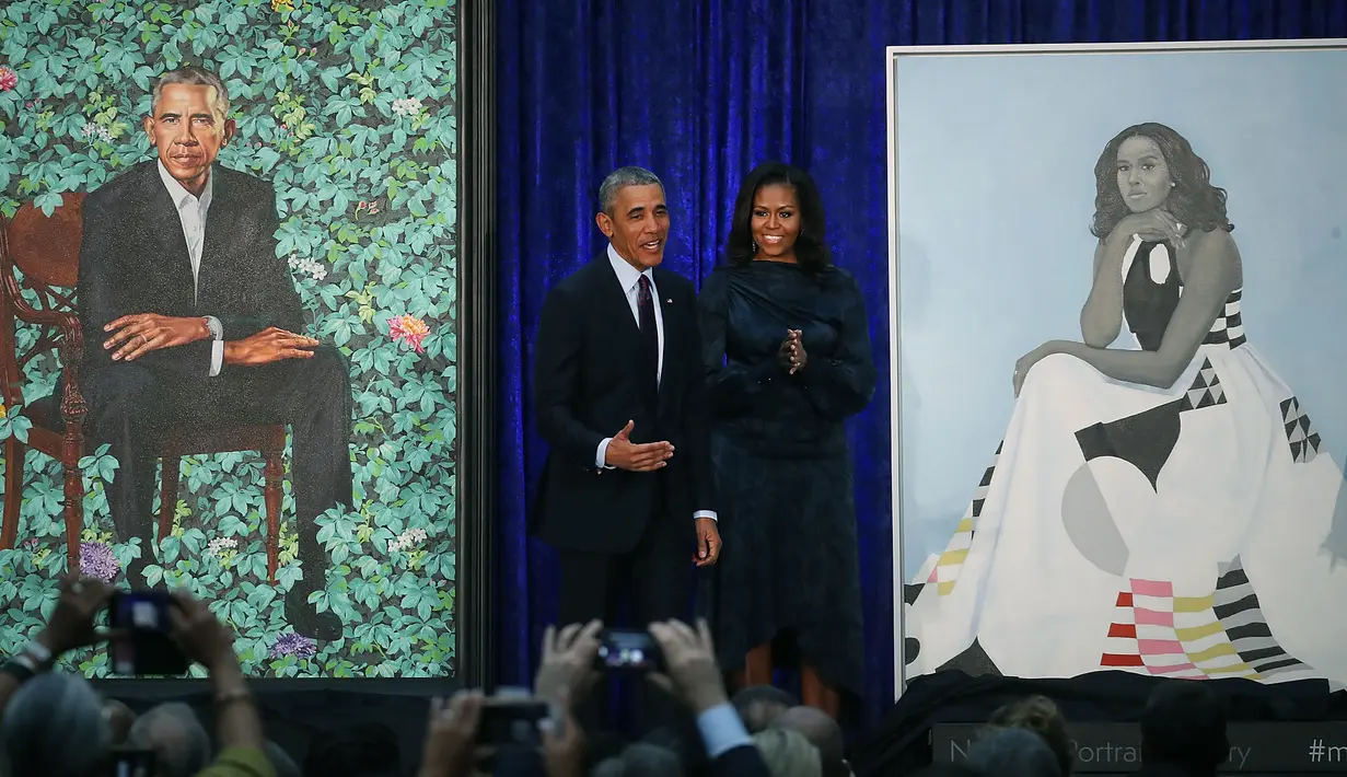 Presiden AS ke-44 Barack Obama bersama istrinya Michelle Obama berdiri di samping lukisan mereka berdua saat upacara peresmian di Galeri Potret Nasional Smithsonian, Washington DC (12/2). (Mark Wilson/Getty Images/AFP)