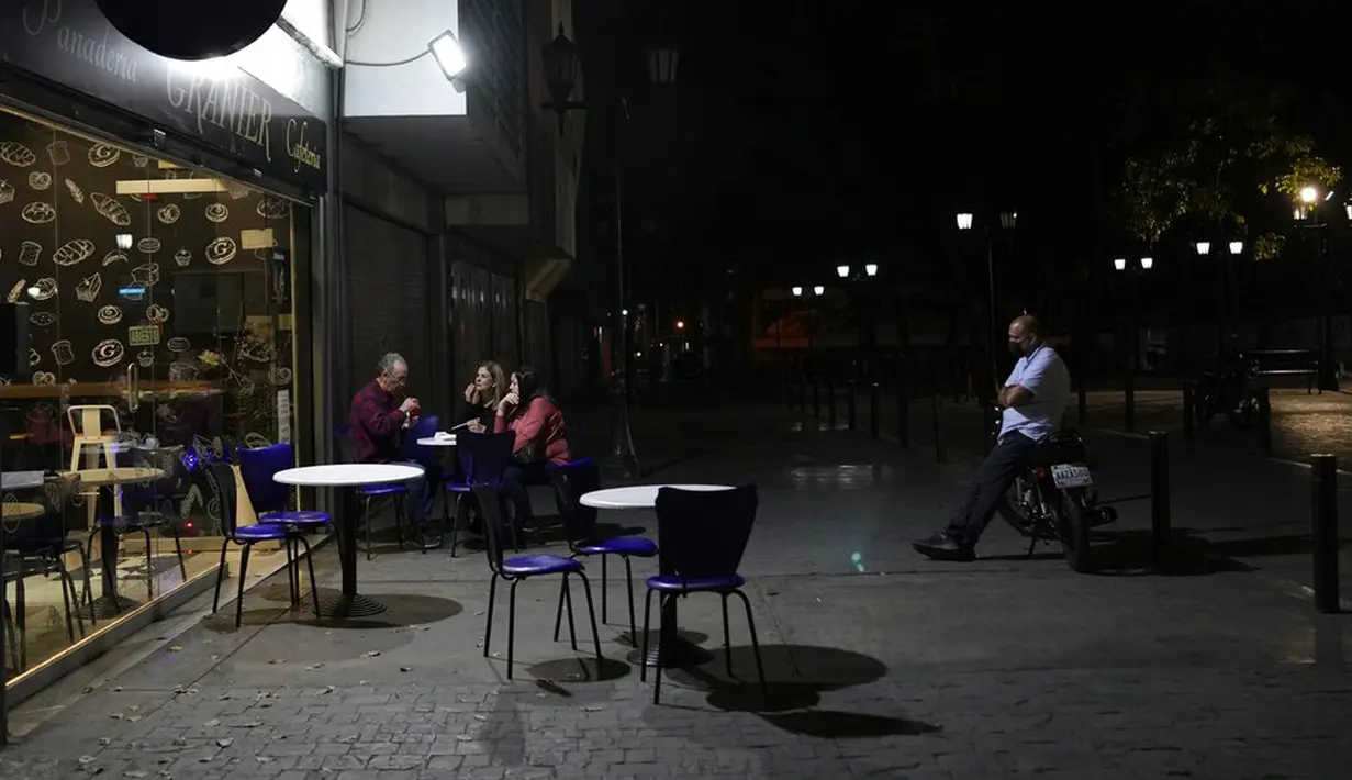 Orang-orang duduk di luar kedai kopi di pusat Kota Caracas, Venezuela, 5 Februari 2022. (AP Photo/Ariana Cubillos)
