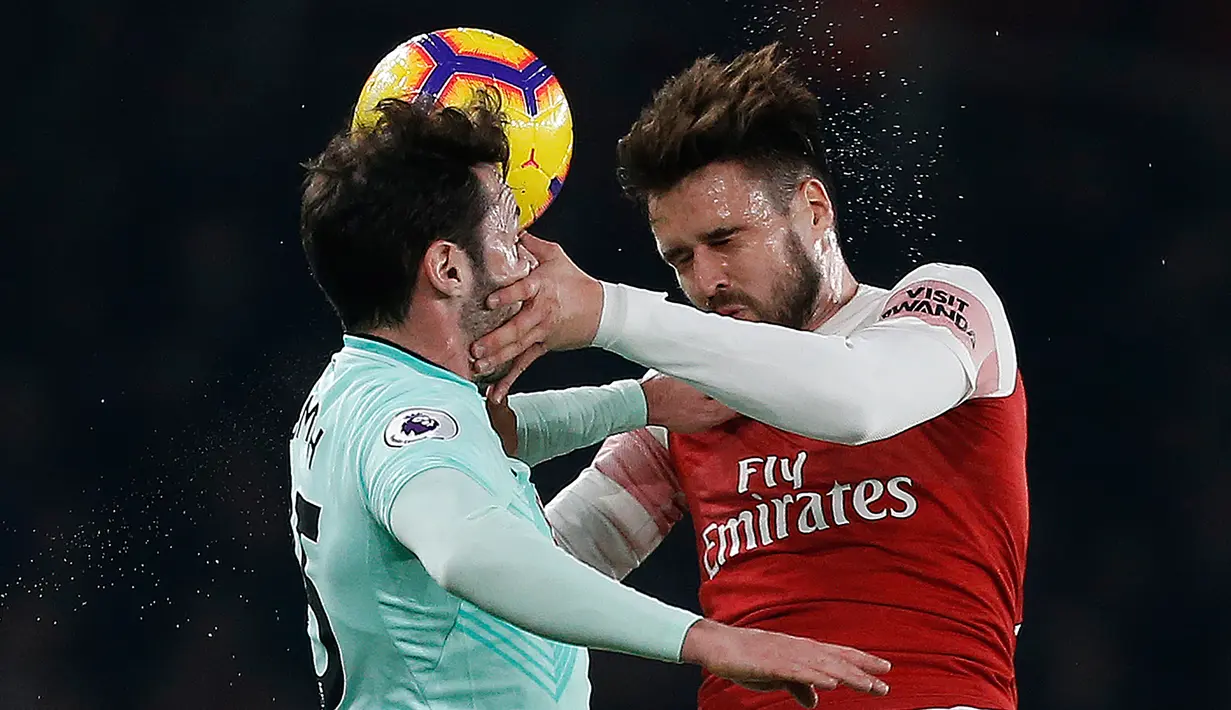Duel udara bek Bournemouth, Adam Smith (kiri) dengan bek Arsenal Carl Jenkinson pada laga lanjutan Liga Inggris, 2018-19 pekan ke-28 di Emirates Stadium, Rabu (27/2). The Gunners menang dengan skor telak 5-1 atas Bournemouth. (Ian KINGTON/AFP)