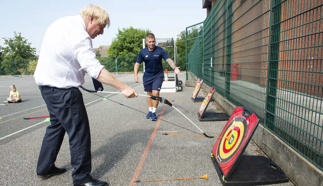 PM Inggris Boris Johnson bermain panahan saat mengunjungi Premier Education Summer Camp di Sacred Heart of Mary Girl's School, Upminster, Inggris, Senin (10/8/2020). Kunjungan Boris untuk melihat persiapan jelang pembukaan kembali sekolah pada September mendatang. (Lucy Young/Pool via AP)