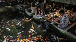 Pengunjung melihat ikan mas berenang di restoran bertema ikan di Chiang Mai, Thailand, Selasa (12/4/2022). (Jack TAYLOR/AFP)