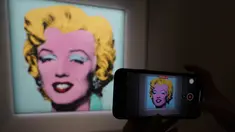 Jurnalis mengambil foto lukisan "Shot Sage Blue Marilyn" karya Andy Warhol selama pratinjau pers di New York, Senin (21/3/2022).  Rumah lelang Christie menyatakan akan melelang lukisan potret Marilyn Monroe yang dibuat Warhol pada 1964 tersebut pada Mei mendatang di New York. (TIMOTHY A. CLARY/AFP)